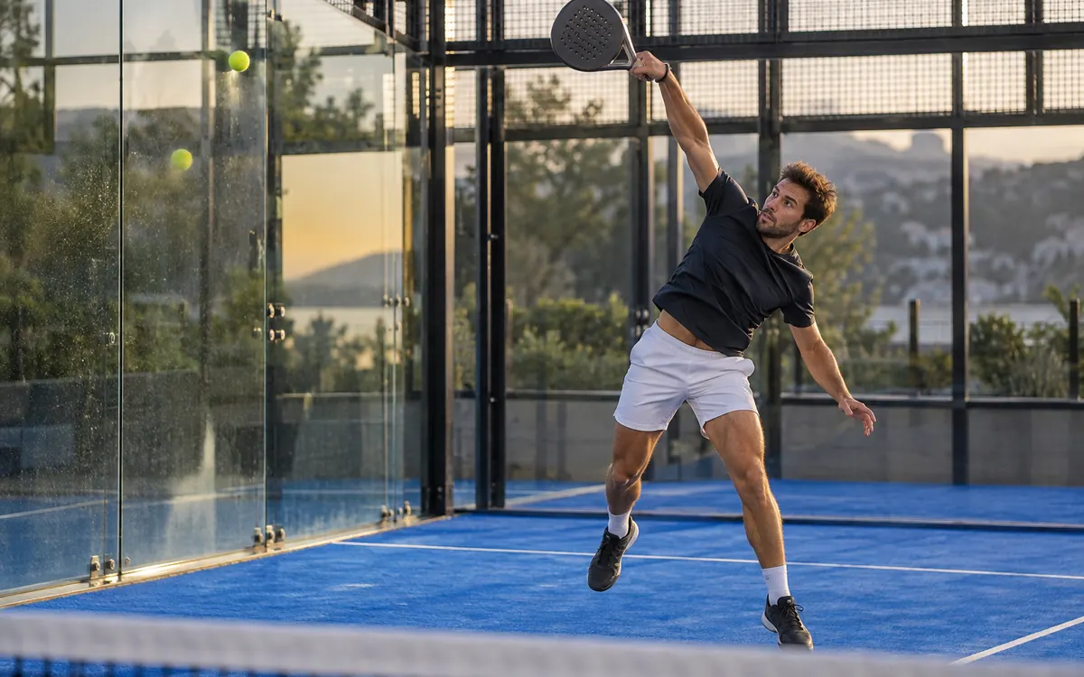 Bajada au padel : frappe en smash après le rebond de la balle sur la vitre du fond