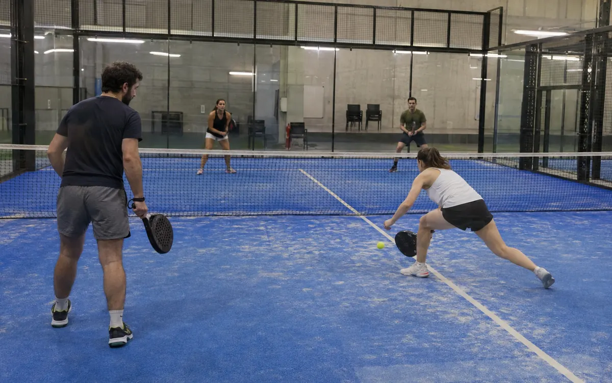 Double de padel dans une salle couverte : vitres, grillage et éclairage de plafond