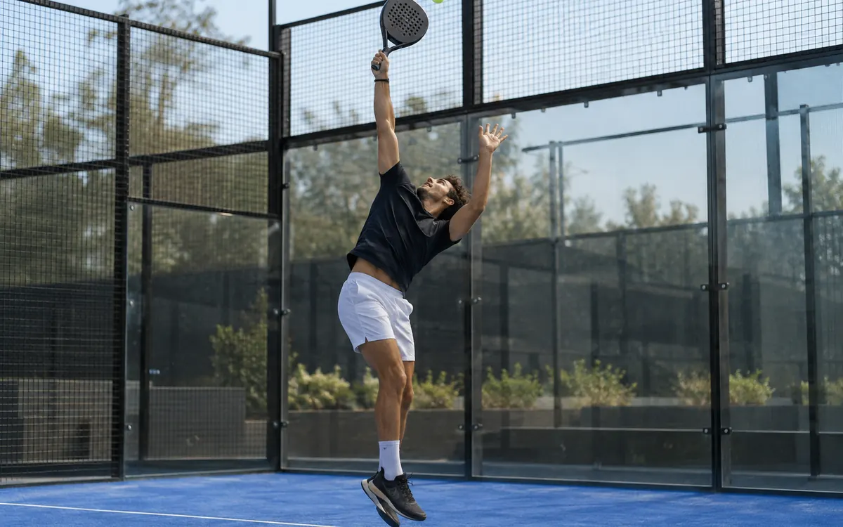 Smash au padel : raquette en extension au-dessus de la tête au moment du contact