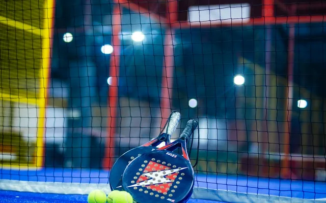 Raquettes de padel posées contre le filet, prêtes pour réserver une partie