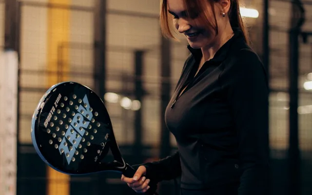 Joueuse tenant sa raquette lors d'une séance de padel sur un court vitré